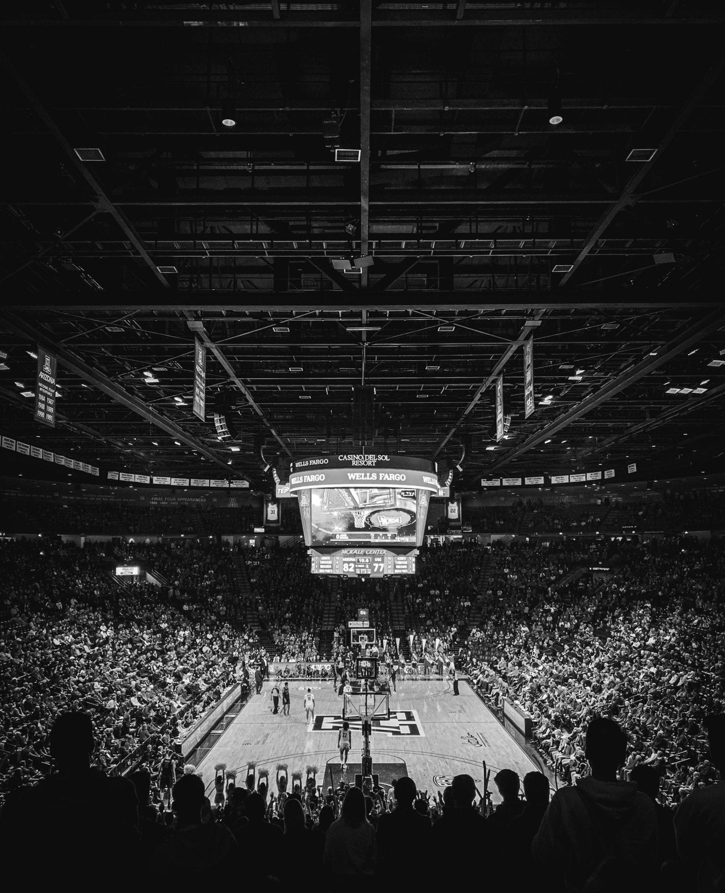 A packed basketball arena seen from the top rows, black and white