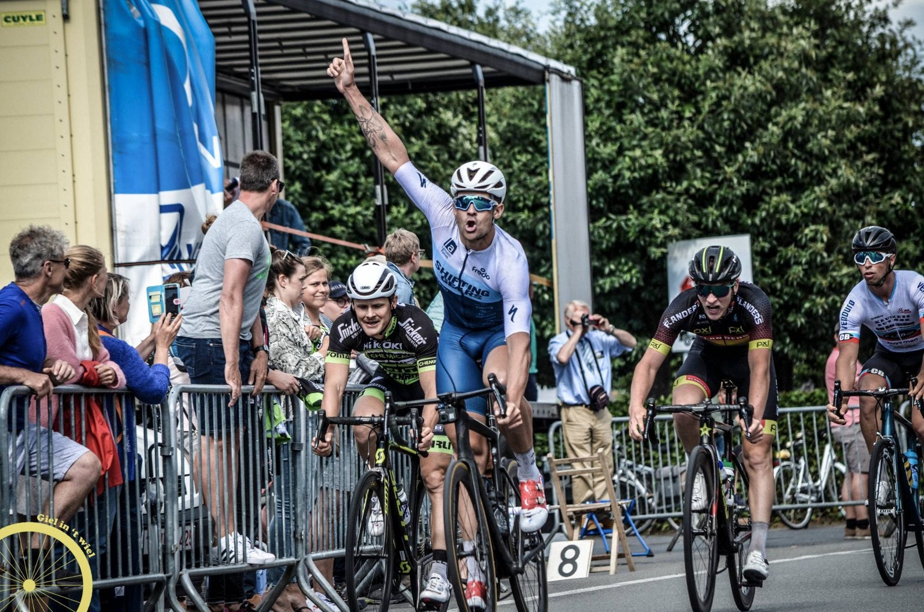 Road cyclists sprinting to the finish, the winner with one arm raised